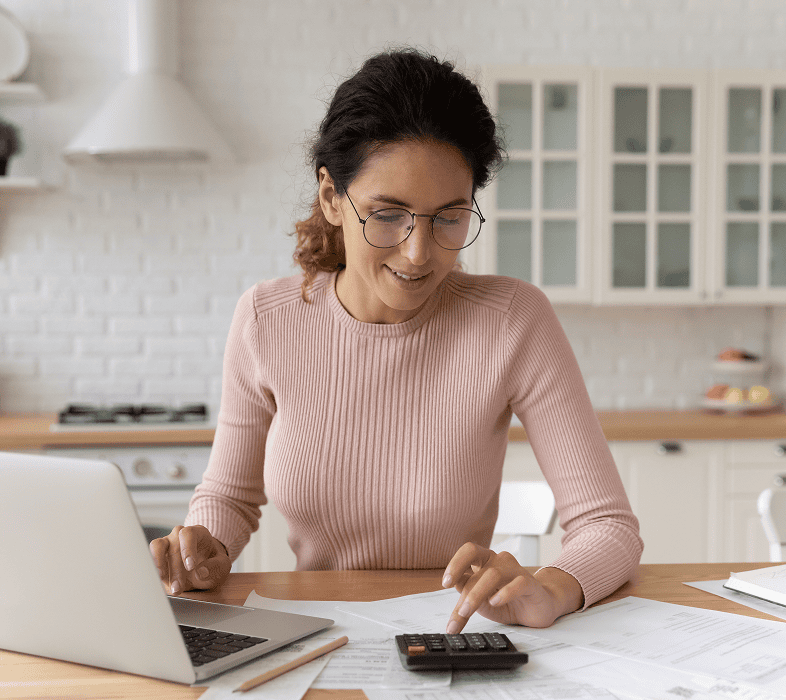 Woman calculating expenses at home with laptop.