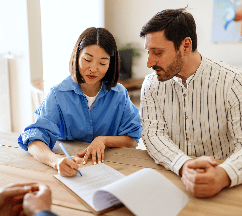 Couple signing documents at a table.