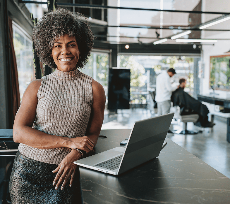 Woman smiling in modern office with laptop.