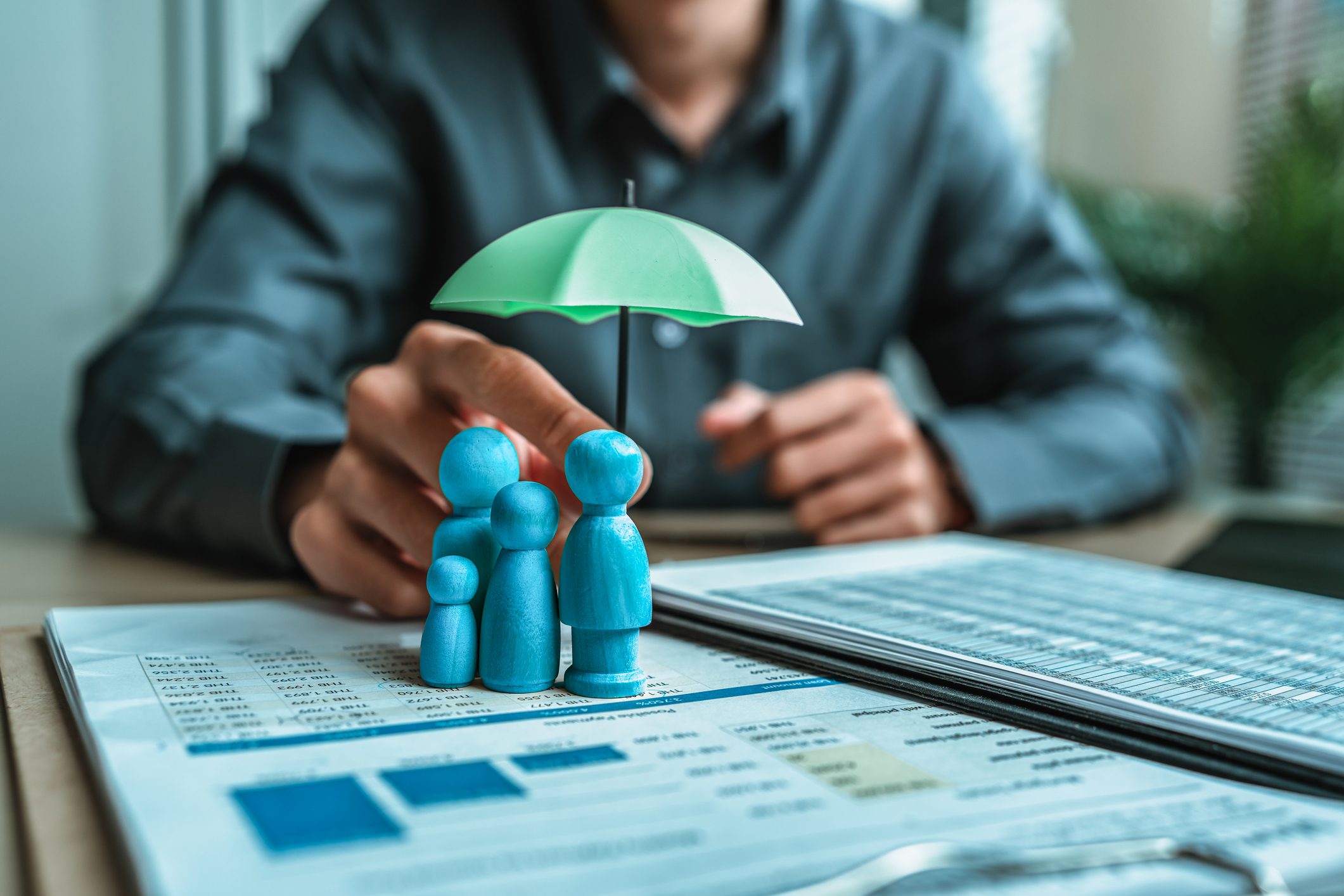 Family figures under umbrella on financial documents
