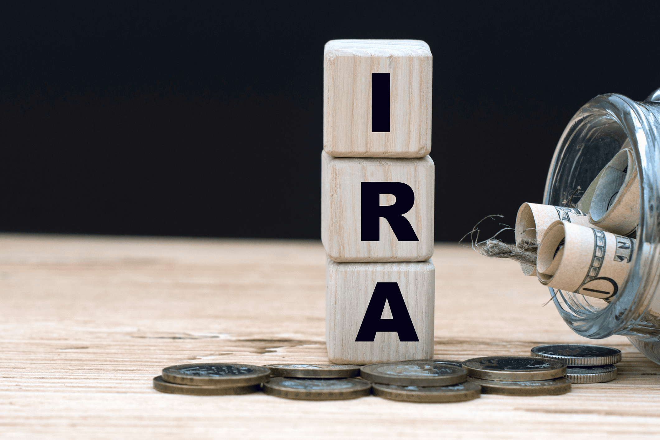 Wooden blocks spelling IRA with coins and cash